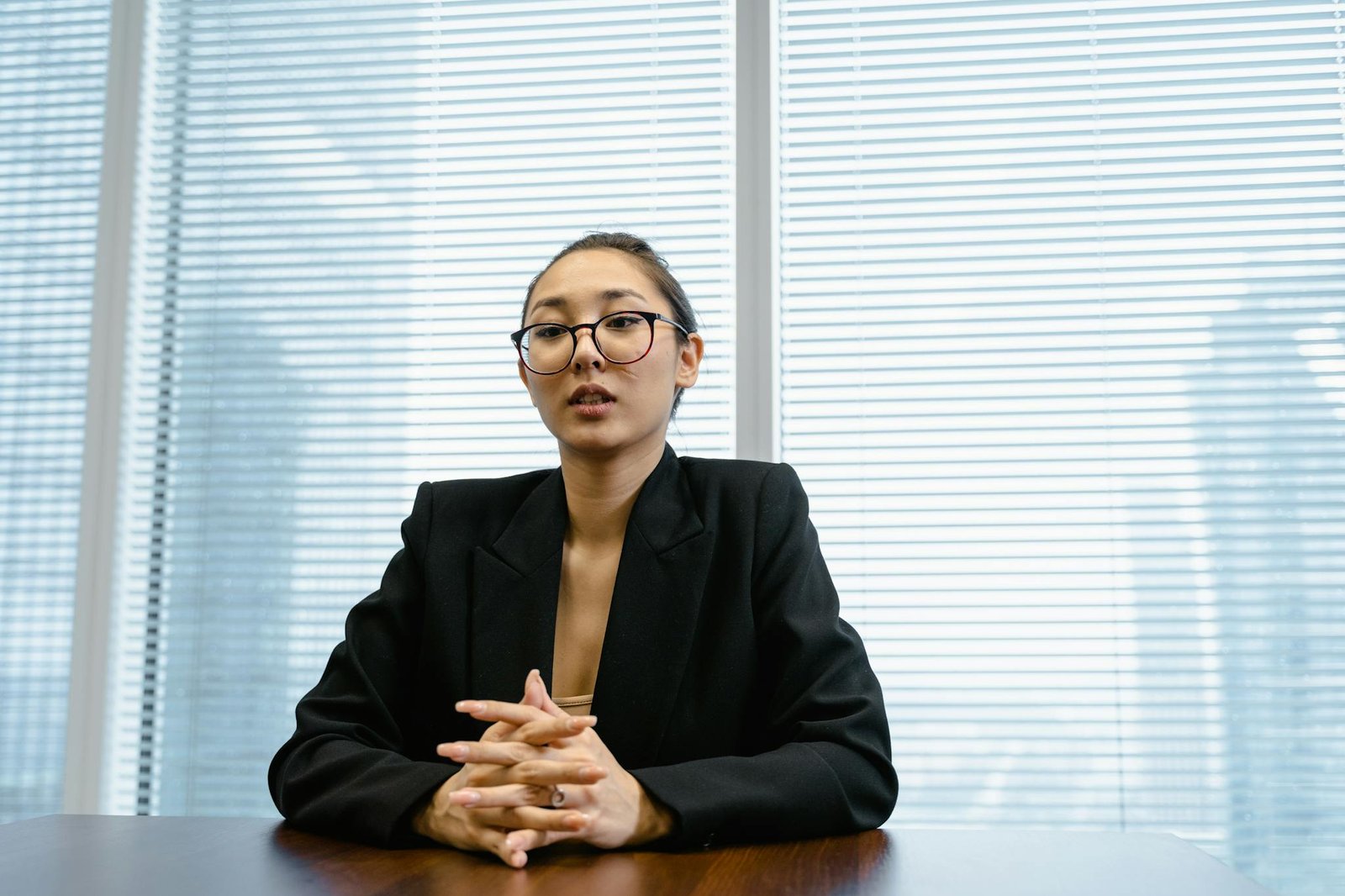Confident businesswoman in formal attire during a meeting in a modern office setting.